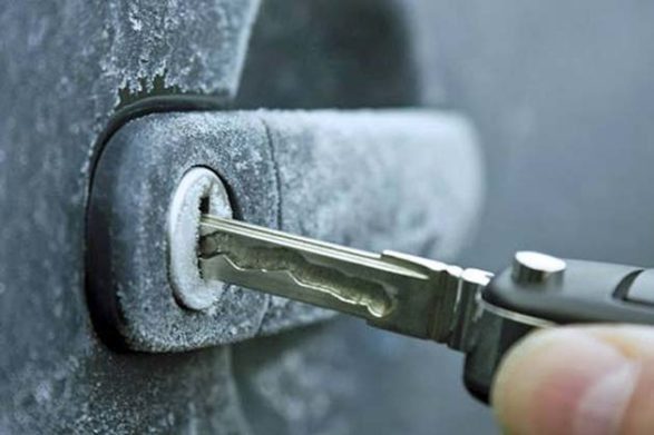 une clé insérée dans une poignée de porte de voiture gelée