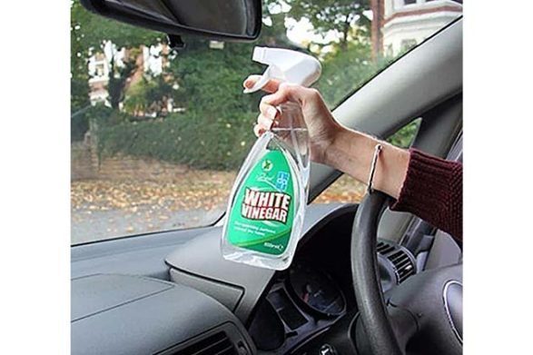 une bouteille de vinaigre blanc pulvérisé sur un pare-brise de voiture pour le nettoyer