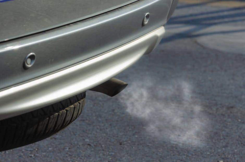 Image illustrant l'erreur Ford DTC P0420, montrant des symboles techniques et une voiture avec un tuyau d'échappement qui émet de la fumée en excès
