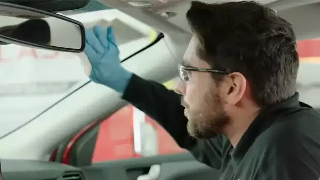 Persona limpiando el parabrisas por dentro