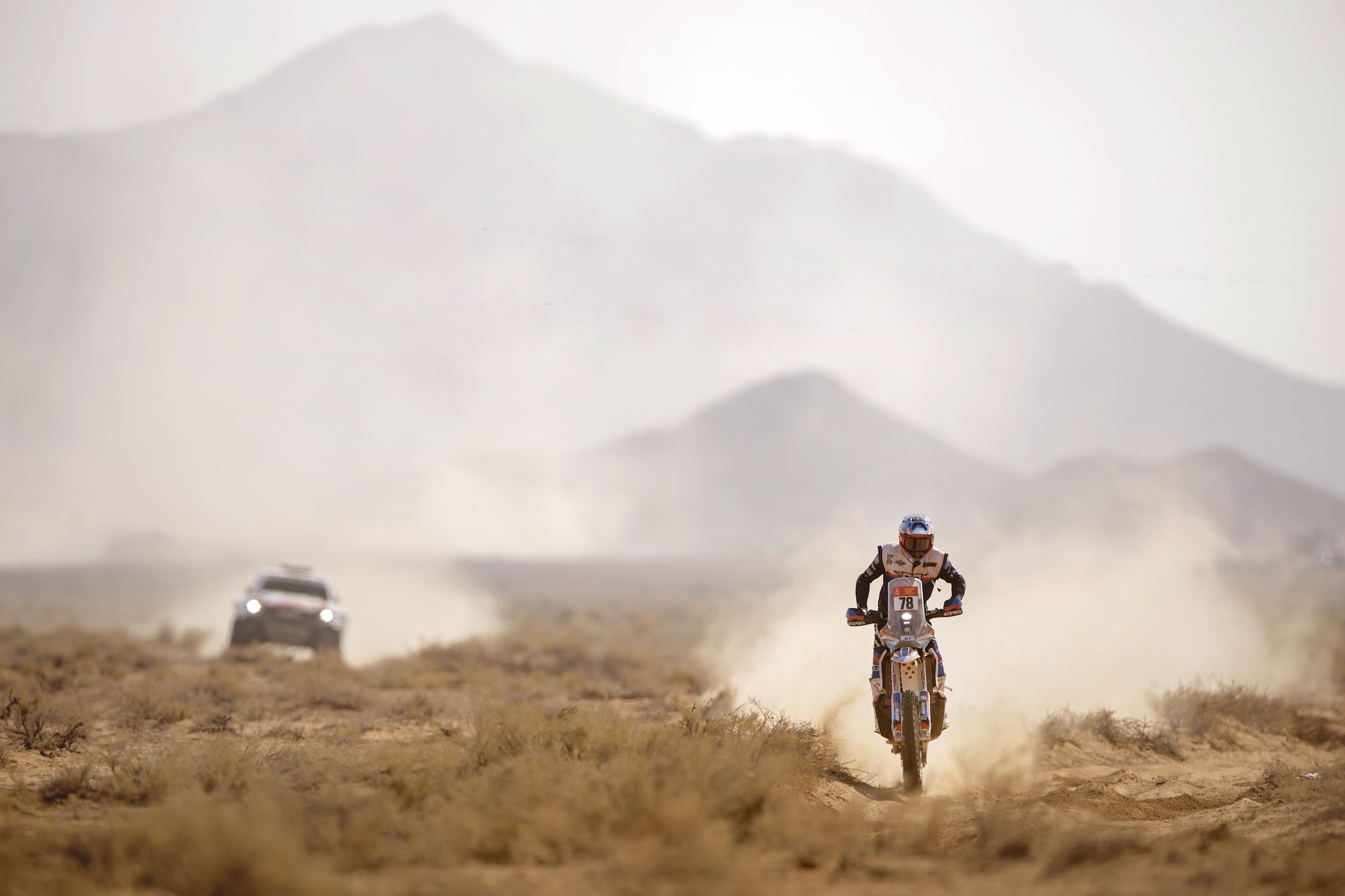 Plan serré sur un Land Rover Defender participant au Dakar, montrant son équipement de raid et sa carrosserie recouverte de poussière.